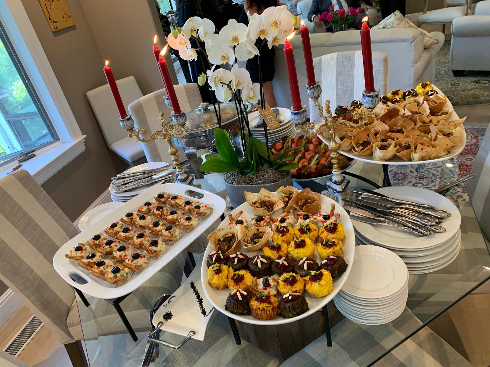 Full catering spread with multiple Persian dishes and candles